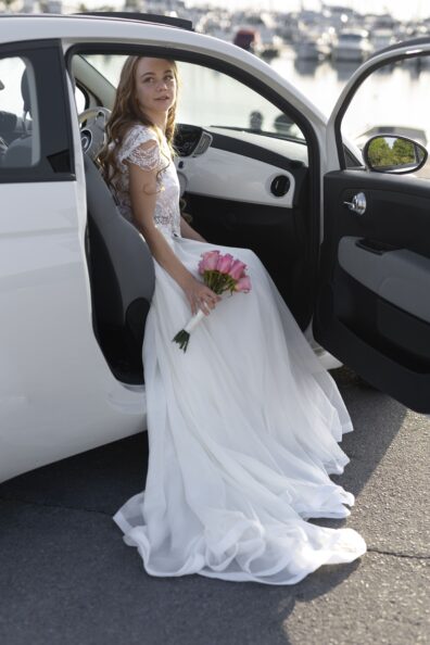 The groom uses the Wedding limo rental service and sits in the car with a handful of flowers.